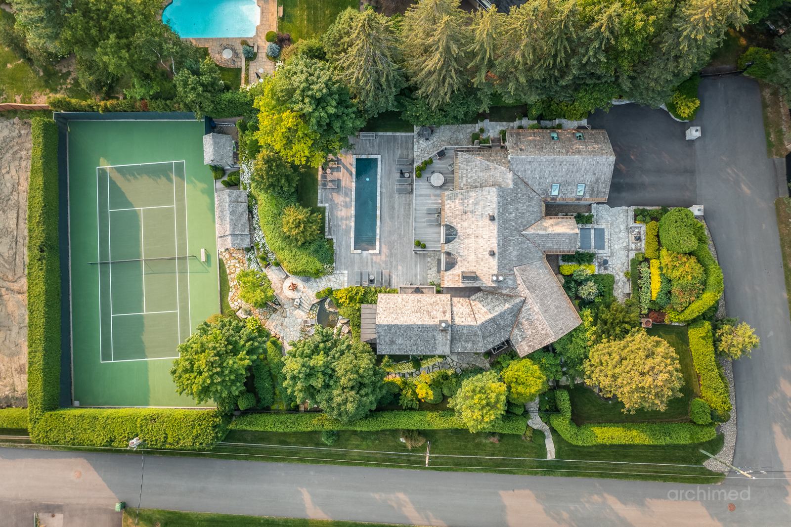 Vue aérienne d'un domaine des Laurentides à Saint-Sauveur, avec sa maison, sa piscine et son court de tennis en pleine forêt