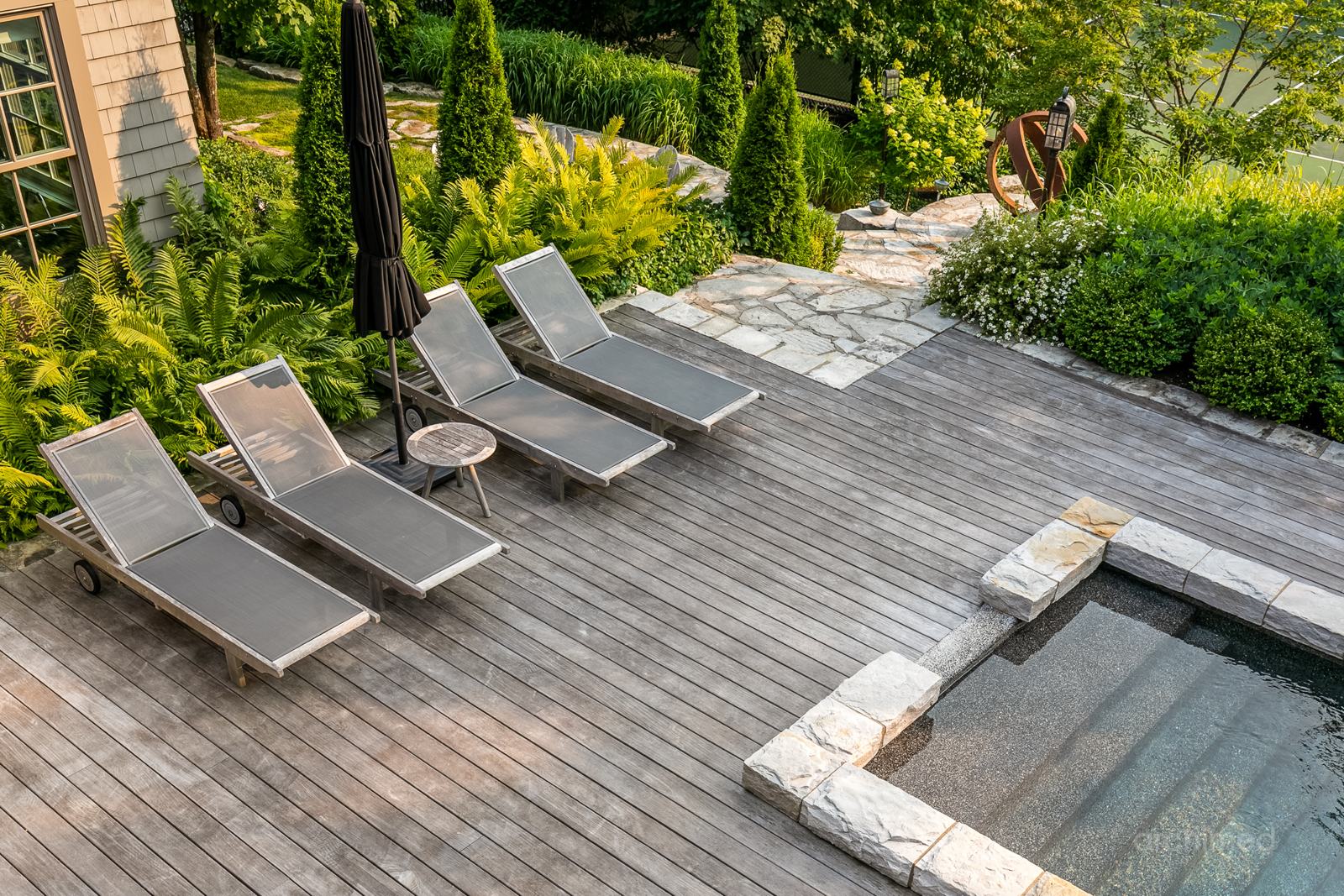 Terrasse en bois et chaises longues dans un jardin paysager