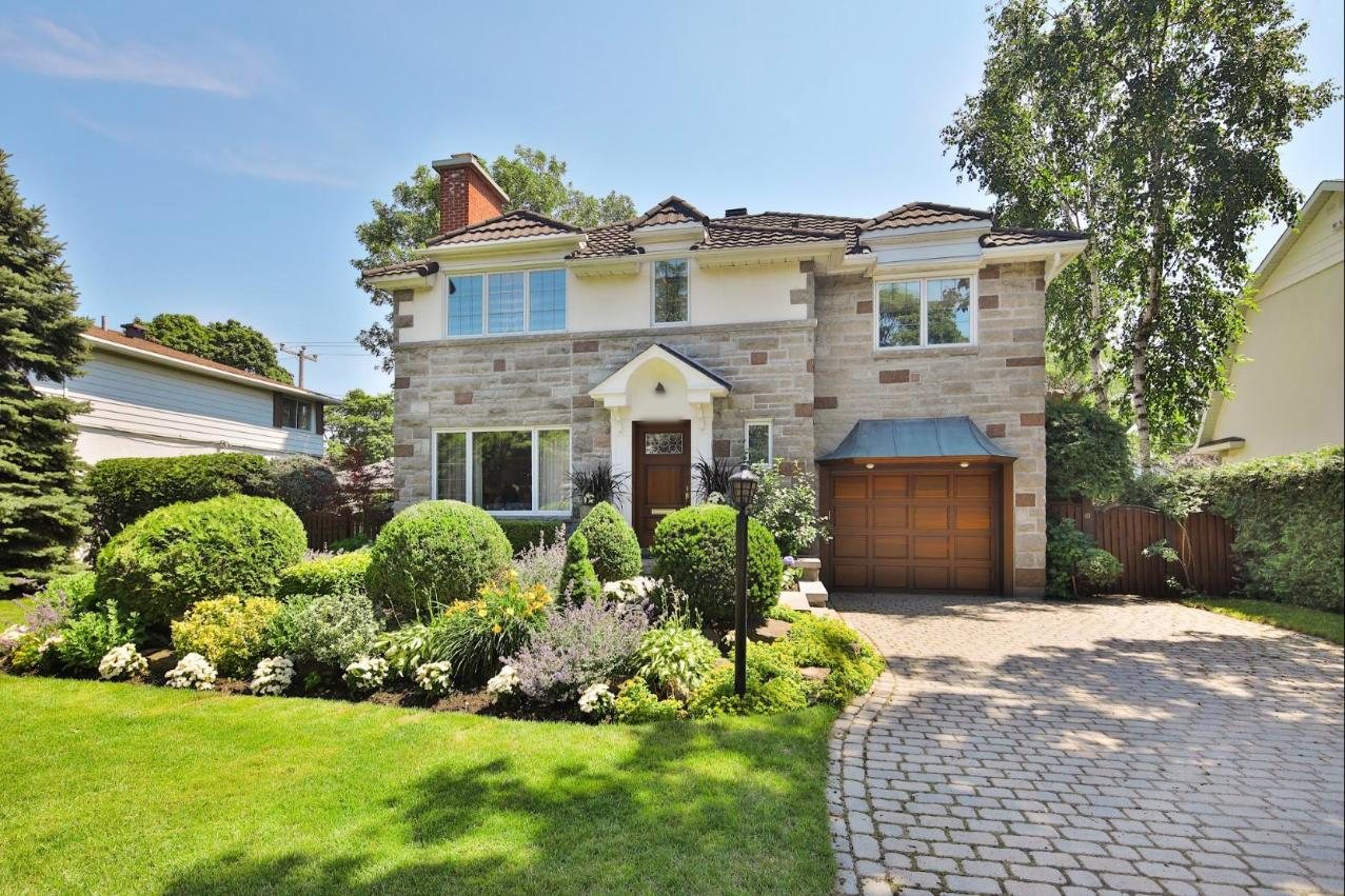 Maison de pierre à deux étages, jardin fleuri et garage, sur une rue résidentielle de Mont-Royal