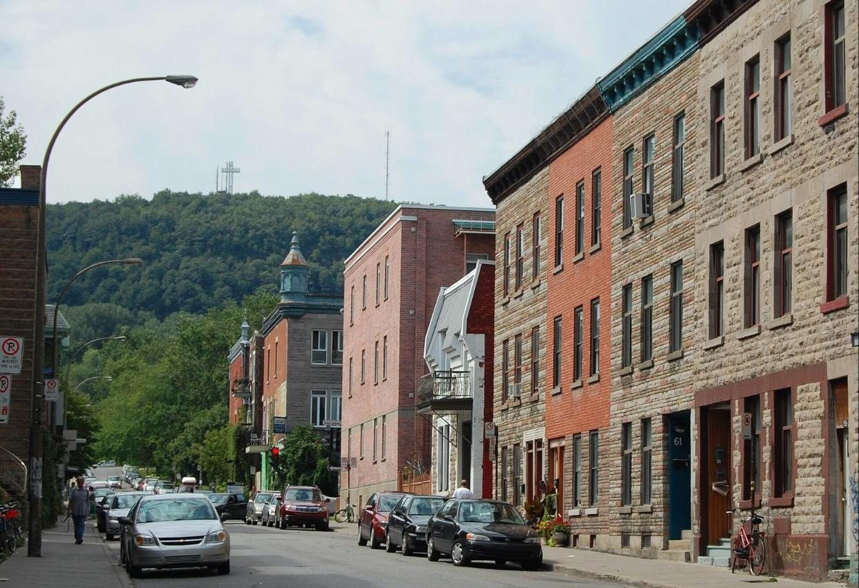 Rue du Plateau-Mont-Royal bordée de façades en brique et en pierre, avec la croix du mont Royal au fond
