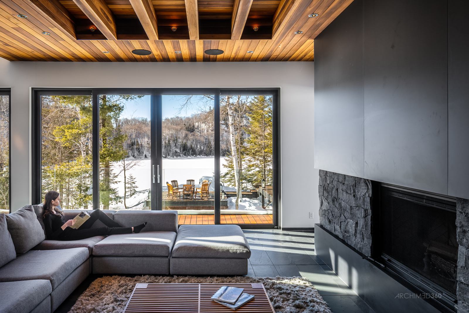 Salon avec foyer en pierre et fenestration sur le lac gelé
