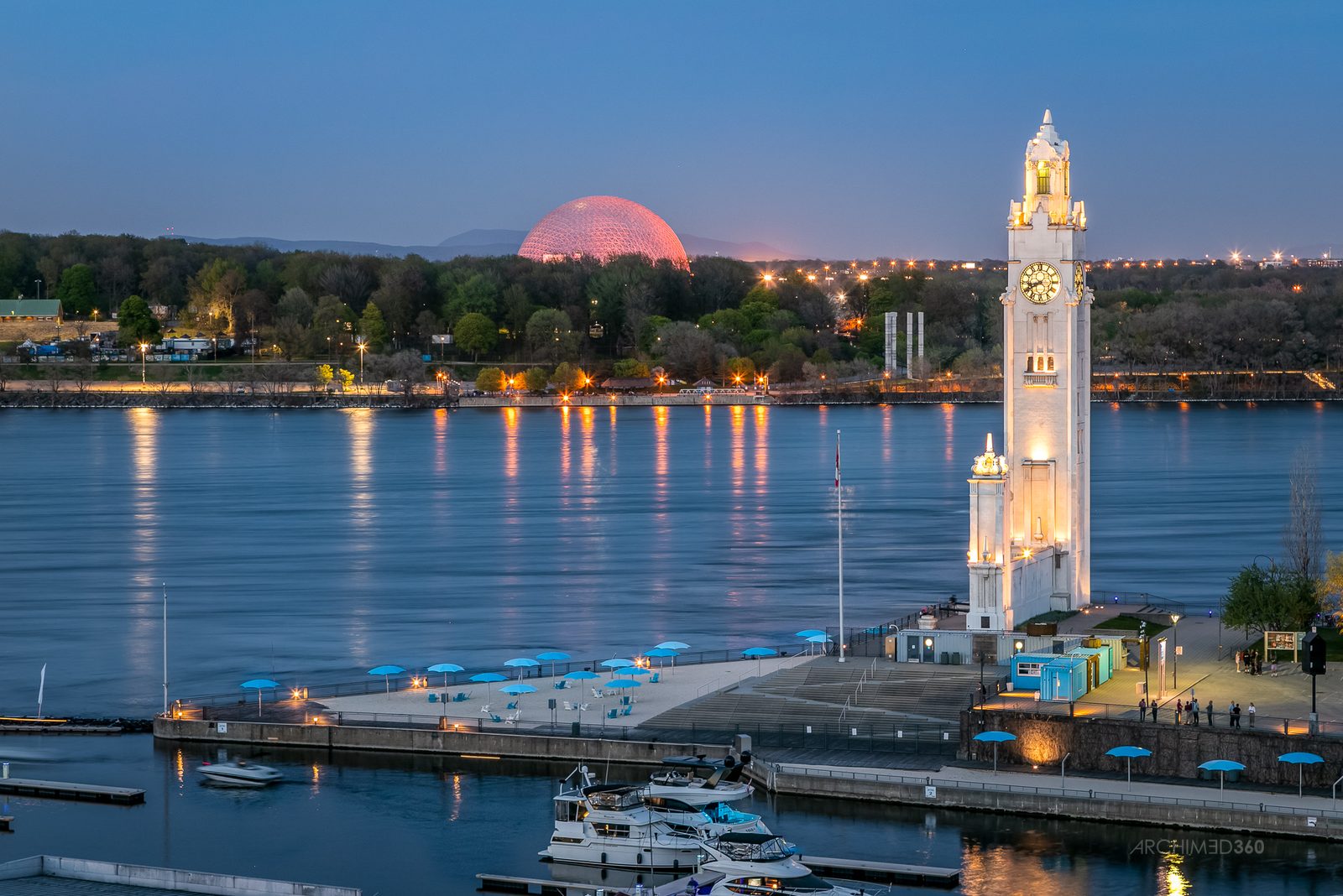 La Tour de l'Horloge du Vieux-Port de Montréal au crépuscule, avec le fleuve Saint-Laurent et la Biosphère au loin